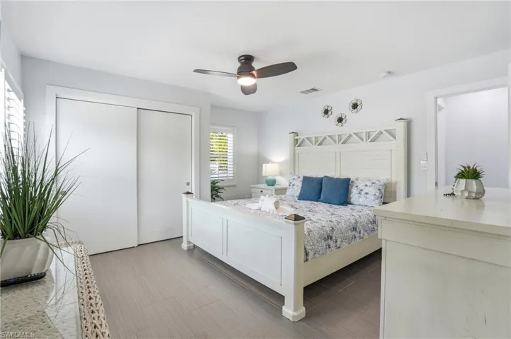 Bedroom featuring wood-finish flooring and white plantation shutters - Virtually Edited Image