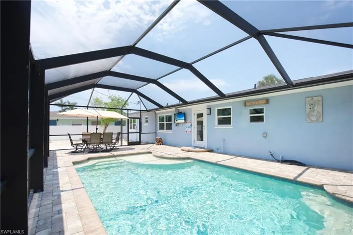 Swimming pool featuring a patio area, a sunroom, and a lanai - Virtually Edited Image