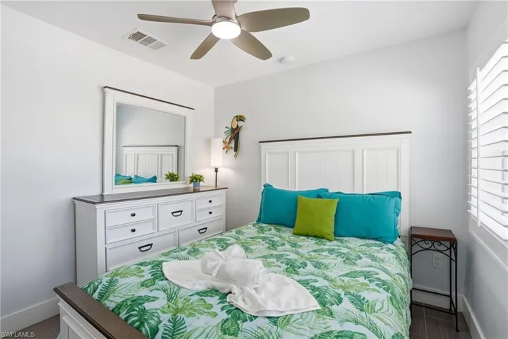 Bedroom featuring a white paneled headboard and a coordinating dresser with dark hardware - Virtually Edited Image