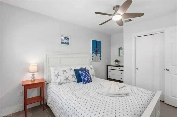 Bedroom featuring a white paneled headboard and wood-finish flooring - Virtually Edited Image
