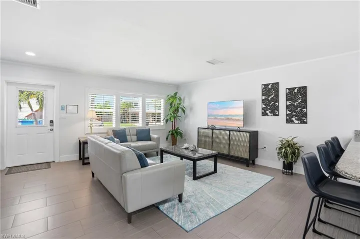 Bright living area featuring light-toned tile flooring, white walls, and recessed lighting - Virtually Edited Image