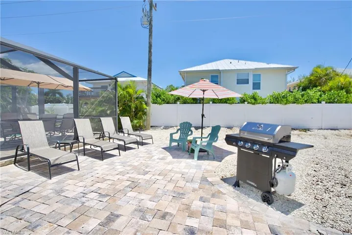 Fenced backyard with a lanai, a patio area, grilling area, and a sunroom - Virtually Edited Image