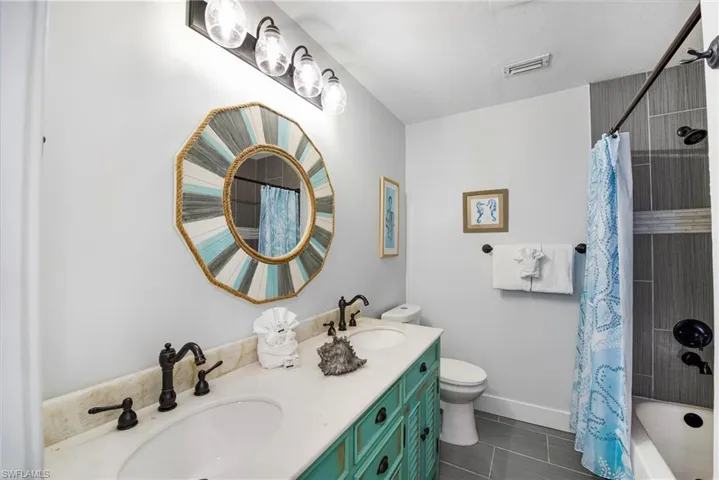 Bathroom featuring shower / bath combo with shower curtain and double vanity - Virtually Edited Image