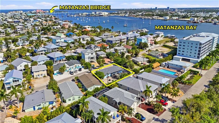 Aerial view of a residential area featuring a body of water with boats and a bridge in the background