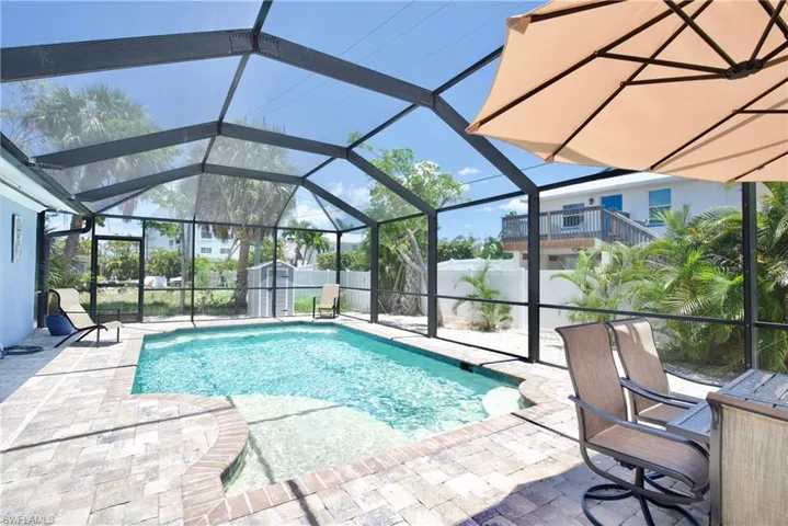 View of pool featuring glass enclosure, a patio, and a fenced backyard - Virtually Edited Image