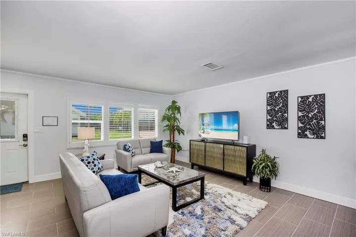 Living area featuring ornamental molding and wood finish floors - Virtually Edited Image