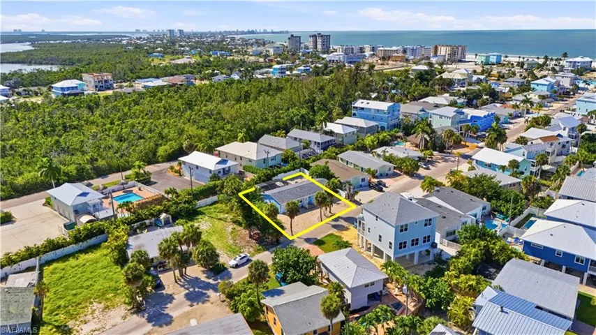 Aerial view highlighting a property within a coastal community, featuring proximity to a body of water and lush green spaces