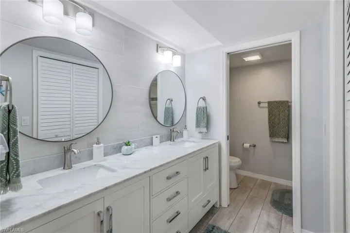 Double vanity with a marble-finish countertop, undermount sinks, and brushed nickel faucets