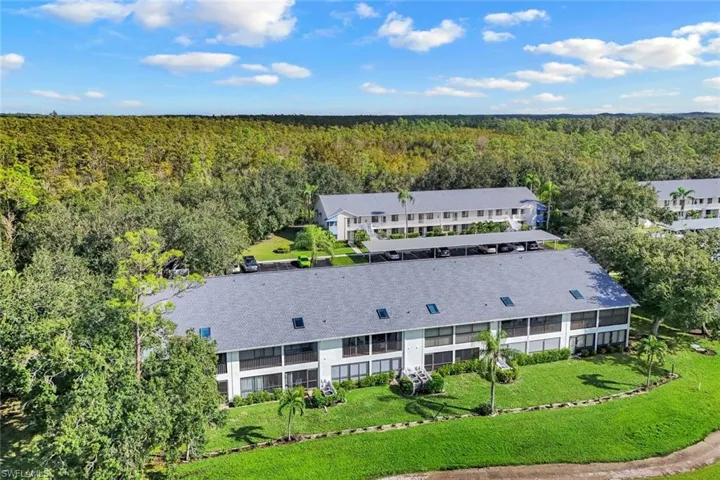 Aerial perspective showcasing multiple multi-story residential buildings with gray shingle roofs, surrounded by extensive green landscaping and mature trees