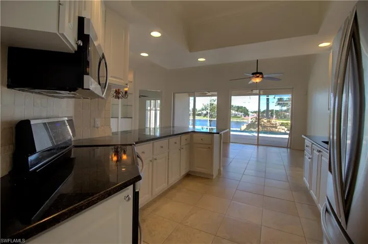 Kitchen featuring stainless steel appliances, white cabinets, a peninsula, recessed lighting, and dark stone counters