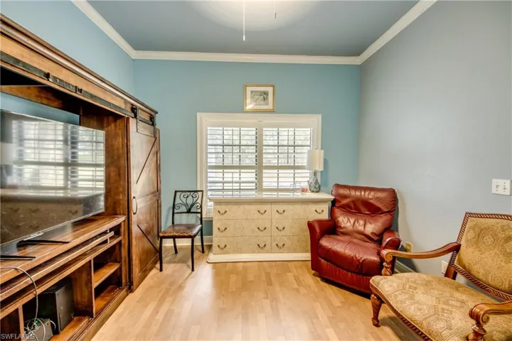 Sitting room with a barn door, light wood-style floors, and crown molding