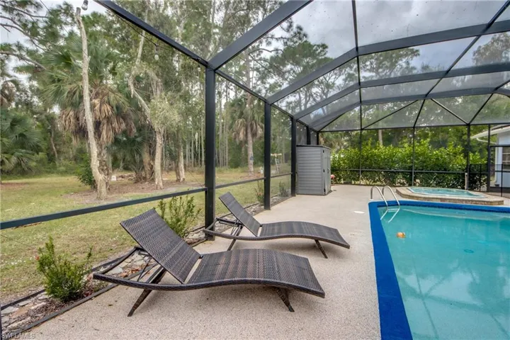 Outdoor pool featuring glass enclosure, a patio, a jacuzzi, a sunroom, and a lawn