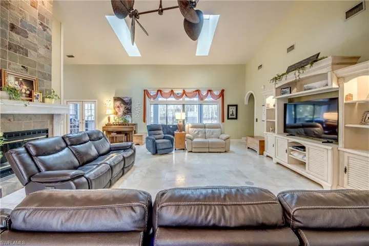 Living room with high vaulted ceiling, a tile fireplace, and a skylight