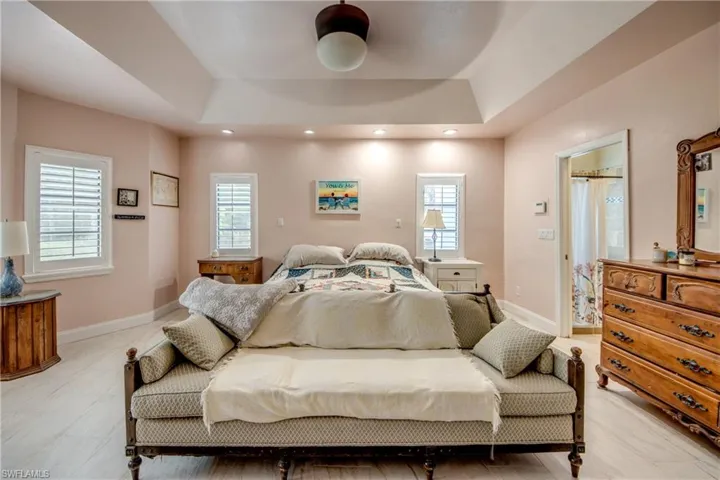 Bedroom featuring multiple windows, recessed lighting, and a tray ceiling