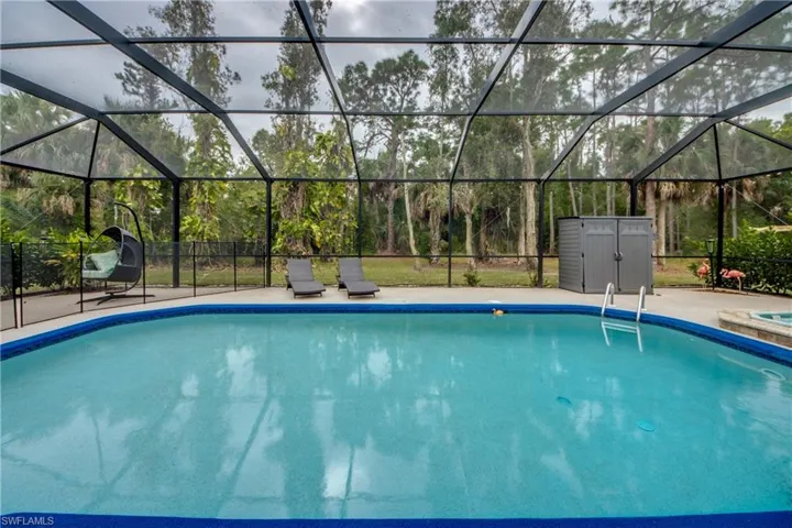 Outdoor pool featuring glass enclosure, a sunroom, and a shed