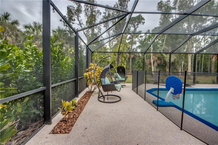 View of pool with glass enclosure, a sunroom, and a patio area