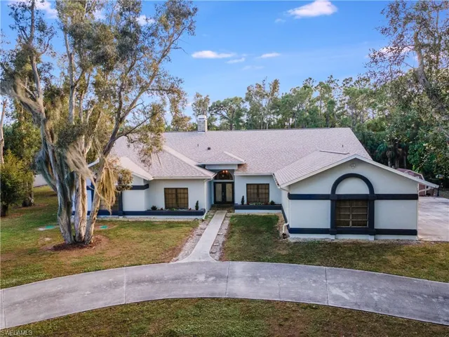 View of front of house with stucco siding, a front yard, a chimney, and a shingled roof