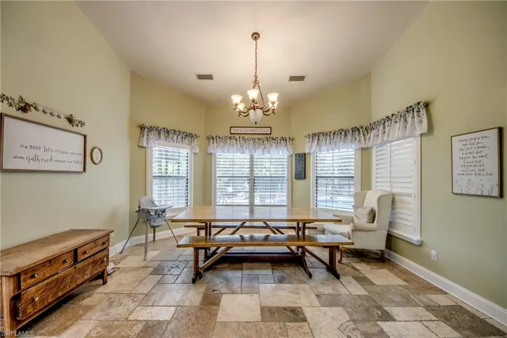 Dining room featuring stone tile flooring and a chandelier