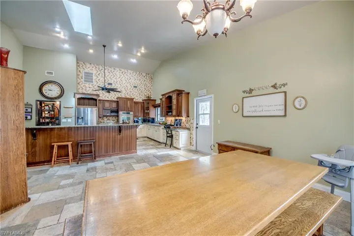 Dining room with a ceiling fan, a skylight, high vaulted ceiling, and stone tile flooring