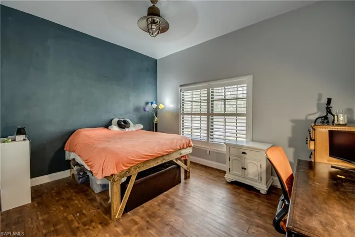 Bedroom with dark wood-type flooring, ceiling fan, and an office area