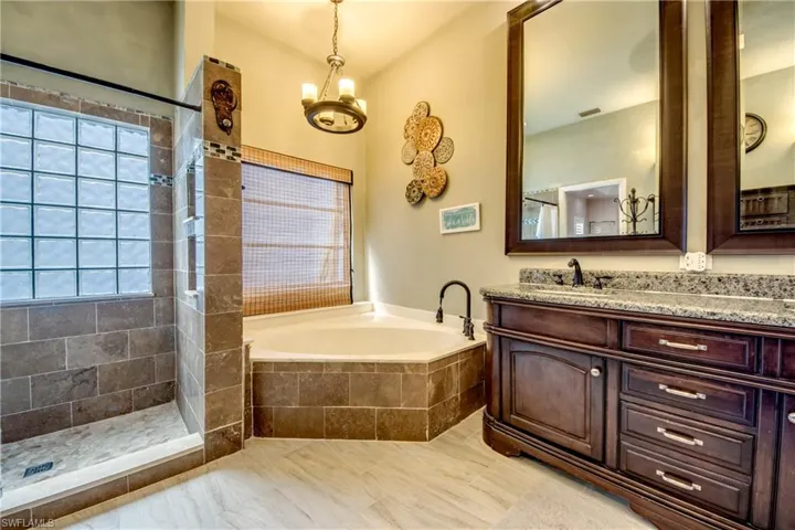 Bathroom featuring vanity, a garden tub, healthy amount of natural light, and tiled shower