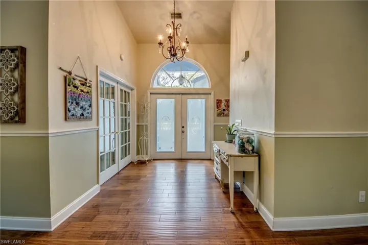 Entryway with french doors, hardwood / wood-style flooring, a chandelier, and a high ceiling