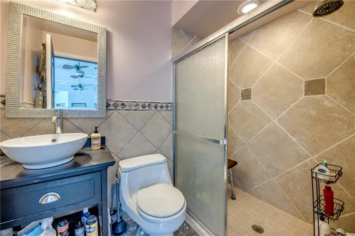 Bathroom featuring vanity, a shower stall, tile walls, and wainscoting