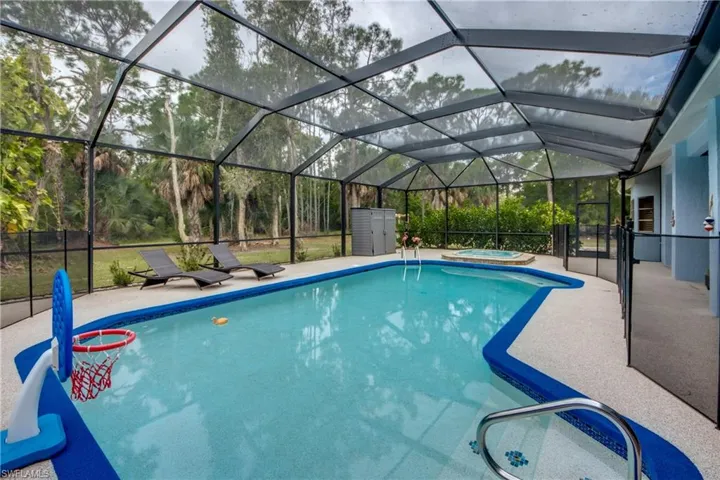 View of pool featuring glass enclosure, an in-ground hot tub, a sunroom, and a patio