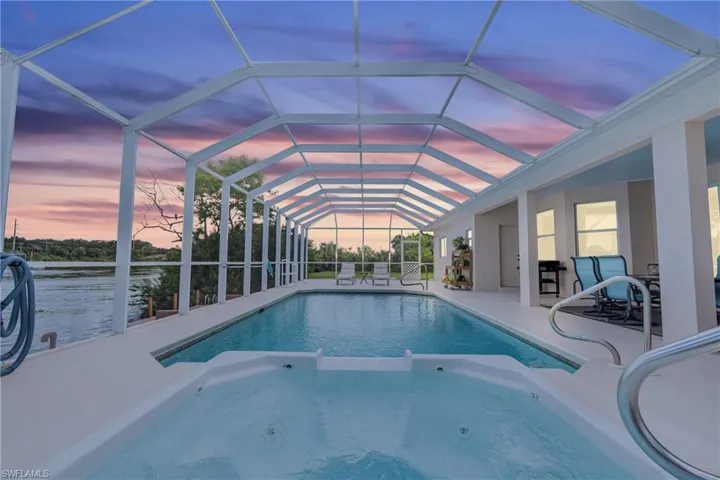 Pool at dusk with a lanai and a patio area