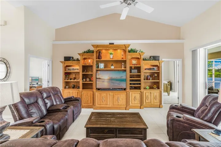 Tiled living room featuring ceiling fan and high vaulted ceiling