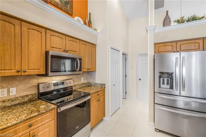 Kitchen with stainless steel appliances, a high ceiling, dark stone counters, and tasteful backsplash