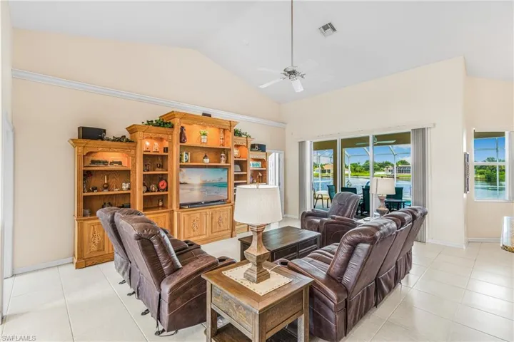 Living room with high vaulted ceiling, ceiling fan, and light tile patterned floors