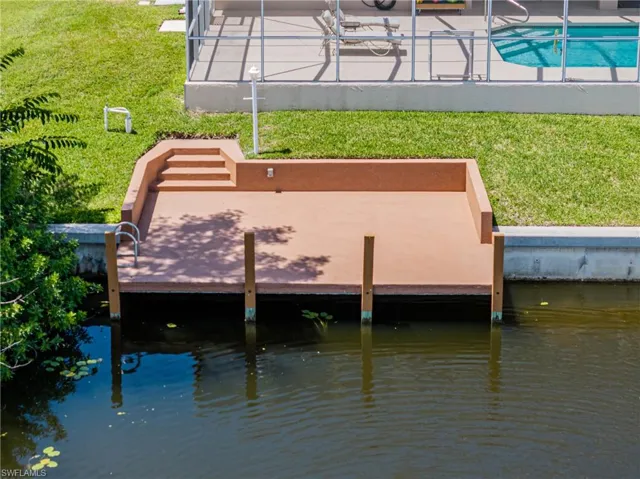 Dock area with a lawn and a water view