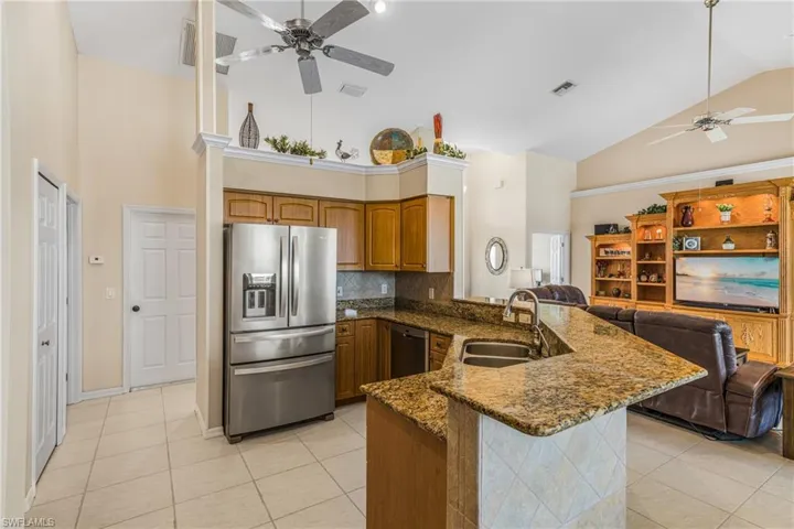 Kitchen with sink, kitchen peninsula, high vaulted ceiling, appliances with stainless steel finishes, and light tile patterned floors