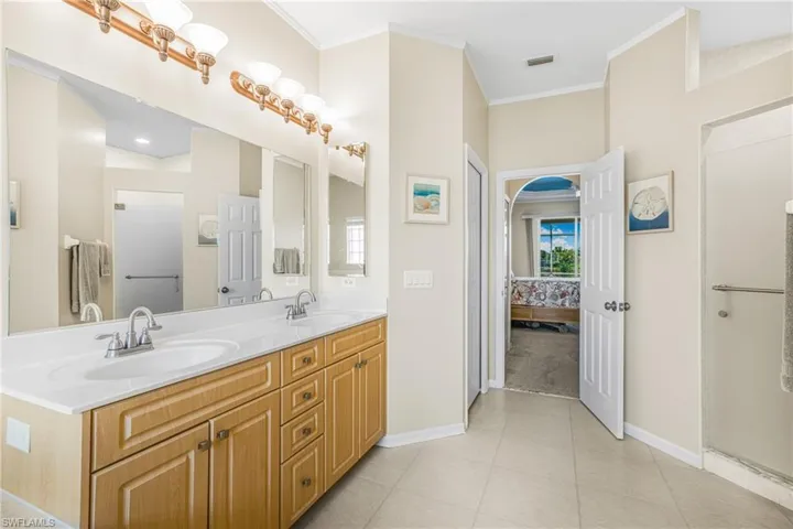 Primary Bathroom with ornamental molding, tile patterned floors, and vanity