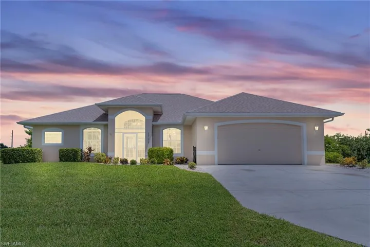 View of front of house with a garage and a yard