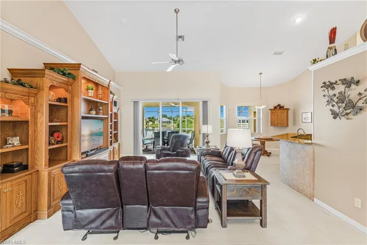 Living room featuring ceiling fan, light tile patterned floors, and vaulted ceiling