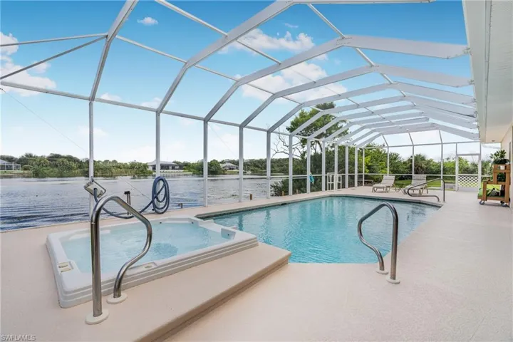 View of pool featuring a water view, glass enclosure, and a patio