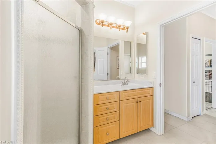 Bathroom with tile patterned flooring, a shower with door, and vanity