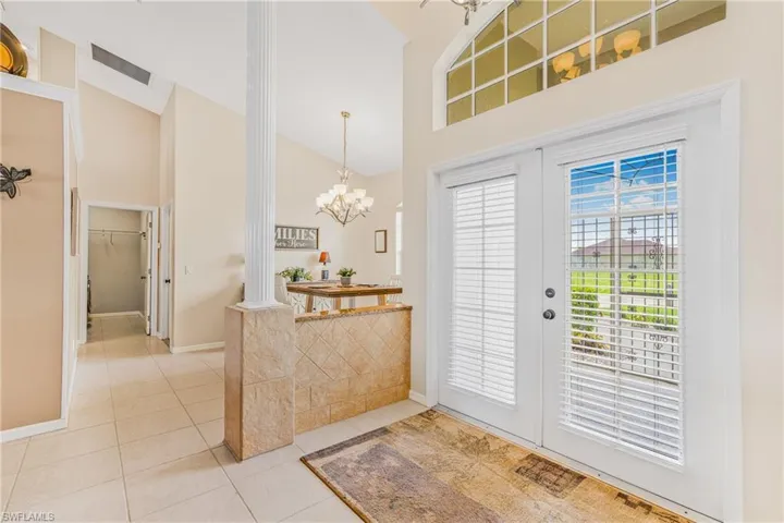 Entrance foyer with high vaulted ceiling, tile patterned floors, a notable chandelier, and a healthy amount of sunlight