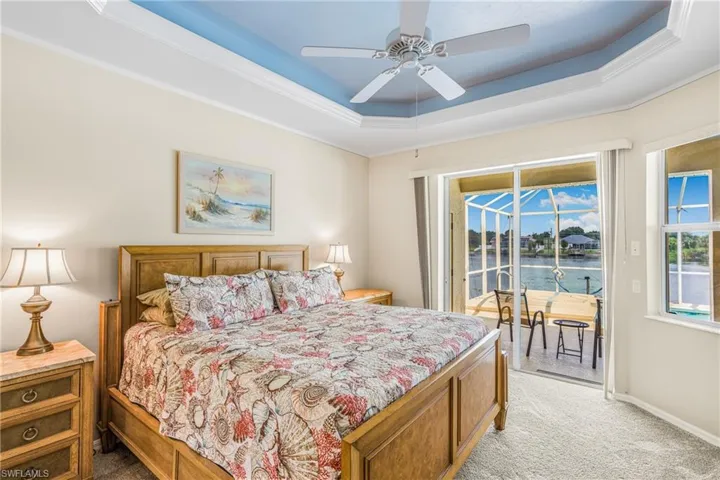 Carpeted bedroom with a water view, ceiling fan, access to outside, and crown molding