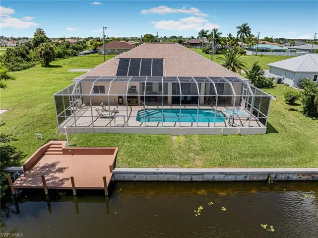 Back of property featuring a yard, a water view, glass enclosure, and a patio area