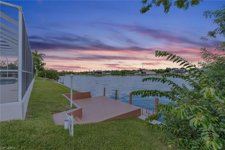 View of dock featuring a yard, glass enclosure, and a water view