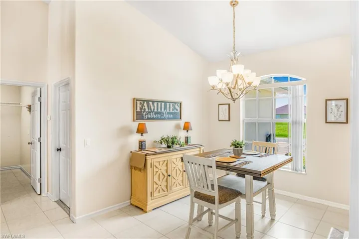 Tiled dining room featuring a notable chandelier and lofted ceiling