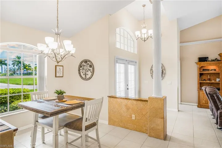 Tiled dining space featuring a notable chandelier, vaulted ceiling, and french doors