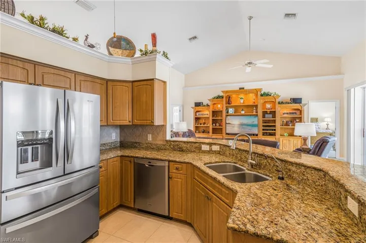 Kitchen featuring dark stone countertops, ceiling fan, appliances with stainless steel finishes, and sink