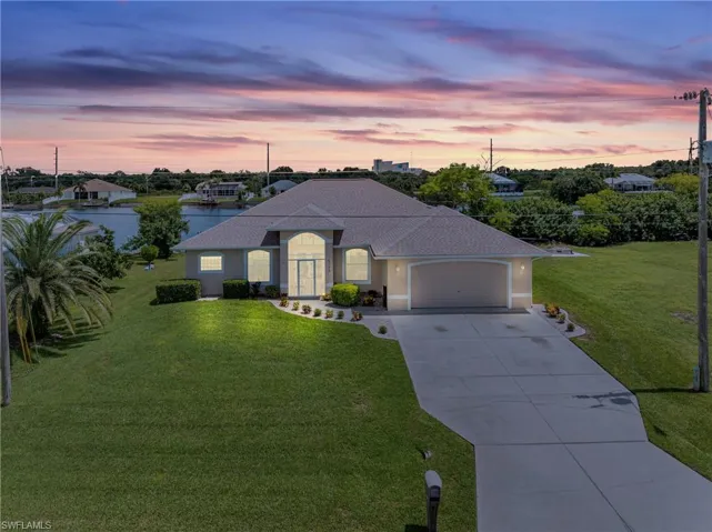 View of front of house featuring a yard, a garage, and a water view