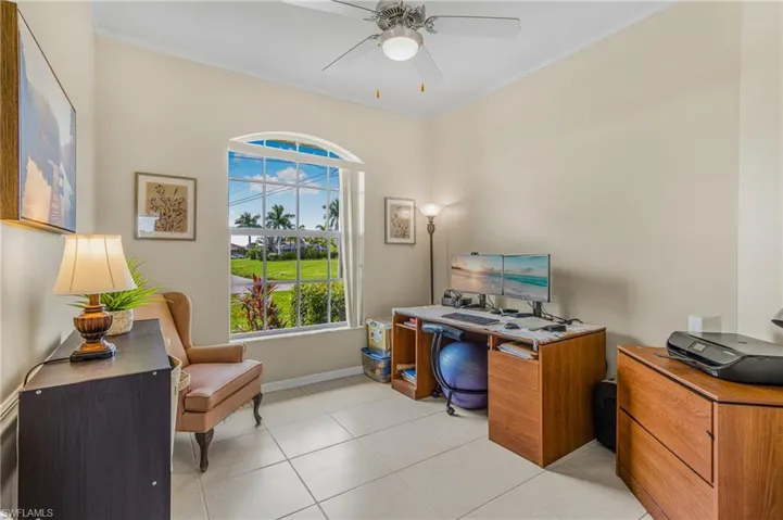Tiled office space featuring ceiling fan and crown molding