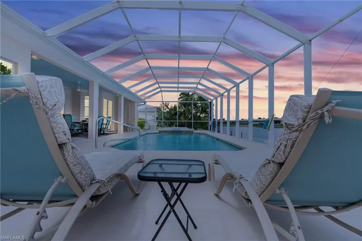 Pool at dusk featuring a patio and glass enclosure