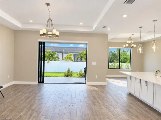 Tray ceiling, recessed lighting, wood-finish flooring, sliding glass patio doors, white cabinetry with polished hardware